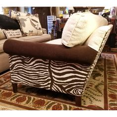 a zebra print chair sitting on top of a rug in front of couches and pillows