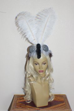 a mannequin head wearing a white wig with feathers on it's side