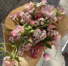 a bouquet of pink and white flowers sitting on top of a brown paper wrapper