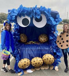 two women standing in front of a blue monster costume