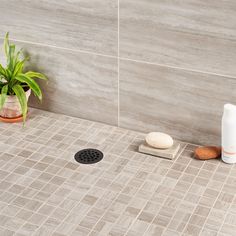 a bathroom with a tiled floor, shower head and soap dispenser on the ground