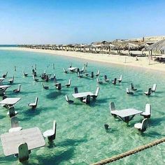 the water is crystal blue and has many benches in it, with arabic writing above them