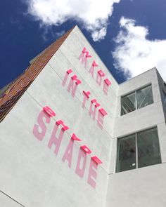 a tall white building with pink lettering on it's side and the words made in the shade