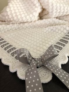 a crocheted blanket with a gray bow on the edge and white polka dots