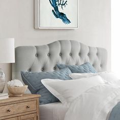 a bed with white sheets and blue pillows