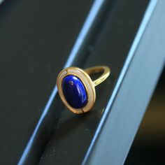 This ring has attracted a lot of attention for its simple yet elegant design. The ring face is inlaid with a deep blue lapis lazuli, the stone surface is smooth and round, the color is deep, giving people a feeling of tranquility and depth. The combination of gold and dark blue is both classic and modern, suitable for various occasions. Whether worn everyday or for formal occasions, this ring can add a sense of elegance and confidence to the wearer. Timeless Blue Oval Cabochon Jewelry, Timeless Blue Signet Ring With Polished Finish, Timeless Blue Gemstone Signet Ring, Elegant Blue Enamel Ring With Gemstone, Elegant Blue Oval Cabochon Moonstone Ring, Elegant Blue Oval Cabochon Signet Ring, Elegant Blue Enamel Ring, Blue Lapis Lazuli Signet Ring With Gemstone, Blue Lapis Lazuli Gemstone Signet Ring