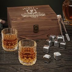 two glasses and ice cubes sitting next to a wooden box