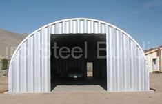 a large metal building in the middle of a desert area with mountains in the background