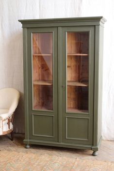 a green cabinet sitting next to a white chair on top of a carpeted floor