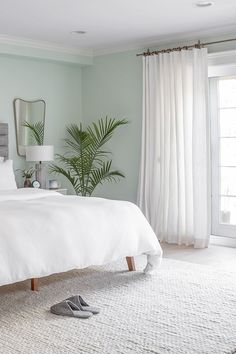 a bedroom with green walls and white bedding, two pairs of shoes on the floor