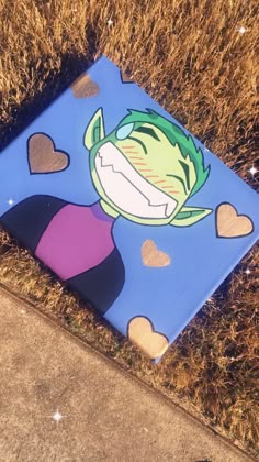 a blue box sitting in the grass with hearts painted on it's sides and an image of a cartoon character