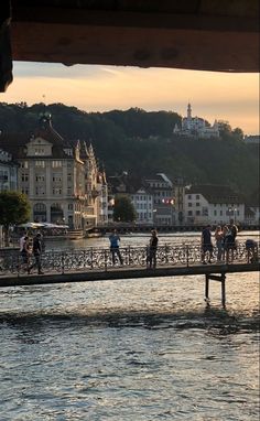 people are walking on a bridge over the water