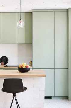 an island in the middle of a kitchen with a bowl of fruit sitting on it