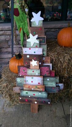 a christmas tree made out of wooden pallets on the ground next to hay and pumpkins