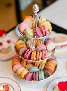 three tiered trays filled with macaroons and pastries on top of a table