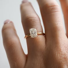 a woman's hand with a gold ring and a diamond in the middle, on top of her finger