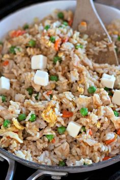 rice with peas, carrots and cheese in a pan on top of the stove