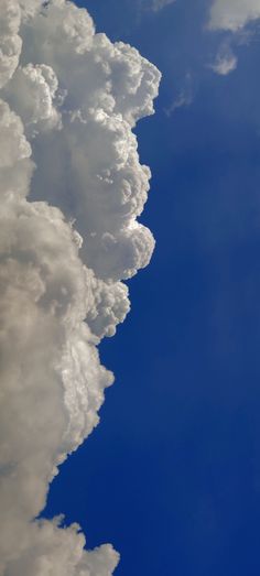 an airplane is flying high in the sky with clouds behind it and blue skies above