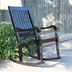 a wooden rocking chair sitting on the sidewalk