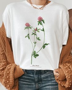 a woman wearing a white t - shirt with pink flowers on the front and green leaves on the back