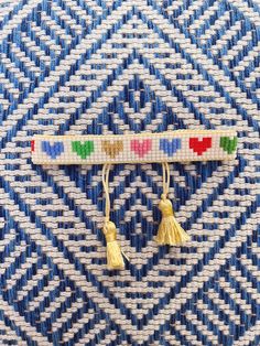 two yellow tassels are hanging on a blue and white woven material pattern with gold colored tassels