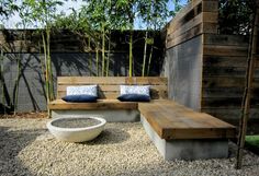 a wooden bench sitting next to a white bowl on top of a gravel covered ground