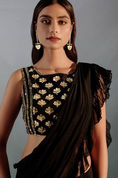 Black concept saree featuring ruffled borders with a fringed pallu and gold sequin mesh pleats. Comes with padded crystal embellished blouse.
Components: 2
Pattern: Embroidered
Type Of Work: Crystal
Neckline: Round
Sleeve Type: Sleeveless
Fabric: Saree: Organza, Blouse: Net
Color: Black
Other Details: 
Feather detail on pallu
Attached contrast pleats
Sheer blouse back
Occasion: Cocktail,Reception - Aza Fashions Concept Saree, Gold Sequin Fabric, Saree Organza, Organza Blouse, Ruffle Saree, Drape Saree, Black Saree, Embellished Blouse, Cocktail Reception