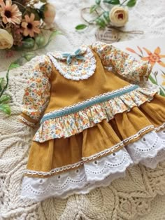 the doll is wearing a yellow dress with white lace trims and flowers on it