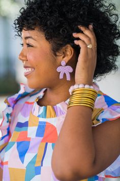 Our Berkeley Bow Earring is an adorable, lightweight beaded statement that adds joy to any outfit! This style is exclusive to The Tiny Tassel and are designed by Mimi's sister, Aiko! All of our earrings are lightweight & hypoallergenic. Earring measures 2 in. L x 1.5 in. W. Playful Beaded Summer Earrings, Spring Multicolor Beaded Earrings, Trendy Purple Earrings For Spring, Colorful Bead Earrings For Spring, Adjustable Beaded Earrings For Spring, Colorful Beads Flower Earrings For Summer, Pink Beaded Earrings For Spring Gift, Colorful Beaded Flower Earrings For Summer, Playful Handmade Hoop Earrings