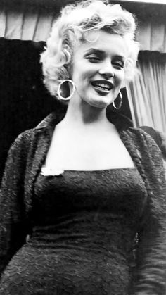 an old black and white photo of a woman with big hoop earrings on her head