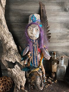 an old doll sitting on top of a wooden table next to bottles and other items