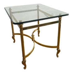 a glass and metal table with gold trimmings on the bottom, against a white background