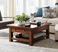 a living room filled with furniture and a table in front of a window on top of a rug