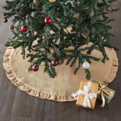 a small christmas tree with presents under it on a round tablecloth covered in burlap