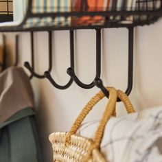 a wicker basket hanging from a black metal shelf next to a wall mounted coat rack