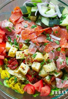 a salad with tomatoes, cucumbers, and other vegetables in a glass bowl