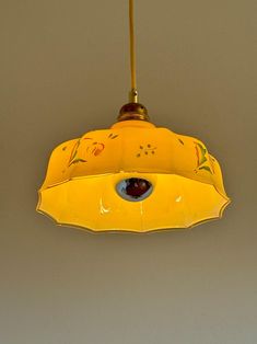 a yellow light hanging from a ceiling with an eye in the center and flowers on it