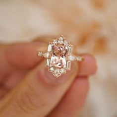 a woman's hand holding a ring with an orange and white diamond in it