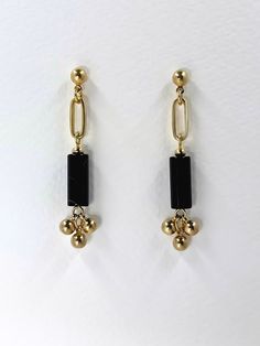 Black, cylindrical cut agate stones feature in these dangle earrings.  The deep black hue of the polished, semi precious stone contrasts beautifully with the warm, golden tone of the brass.  An elongated brass oval holds the stone and three solid brass beads dangle at the bottom.  The occasional, light banding in the black stone creates variation and contributes to the natural, uniqueness of the earrings. The geometric shapes create a modern and elegant design.  All Set Theory jewellery comes with care instructions and a polishing pad to keep your jewels looking shiny and fabulous!✨ Modern Gold Earrings With Black Enamel, Minimalist Black Linear Earrings For Gifts, Minimalist Black Linear Drop Earrings, Minimalist Black Linear Earrings As Gift, Minimalist Black Drop Earrings, Modern Black Long Drop Jewelry, Black Linear Earrings For Pierced Ears As Gift, Black Dangle Linear Earrings For Pierced Ears, Modern Onyx Earrings With Black Enamel