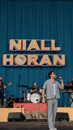 a man standing on top of a stage next to a sign that says nail horan