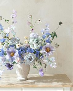 a white vase filled with blue and purple flowers