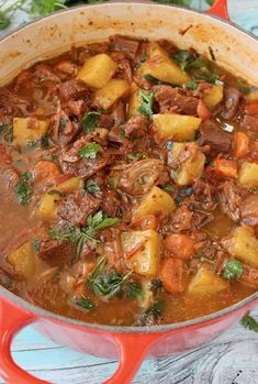 a pot filled with beef and potatoes on top of a table