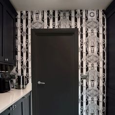 a black and white wallpapered kitchen with an open door