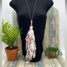 a mannequin wearing a black top with a pink and white scarf hanging from it's neck