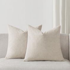 two white pillows sitting on top of a couch