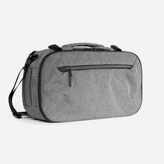 a gray bag with black handles and zippers on the front, sitting against a white background