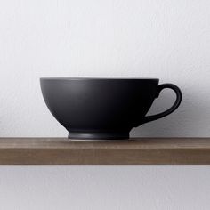 a black bowl sitting on top of a wooden shelf