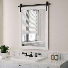 a bathroom sink under a large mirror in front of a window with blinds on the windowsill