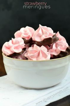 a white bowl filled with pink and chocolate covered desserts on top of a table