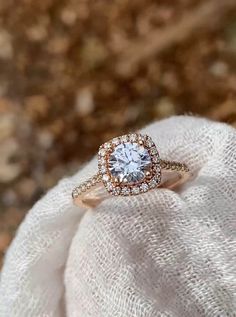 a close up of a person wearing a ring on top of a white cloth with leaves in the background